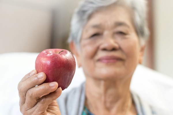 an older asian woman holding an apple
