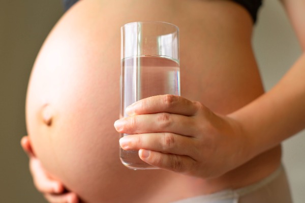 pregnant belly woman holding a glass of water