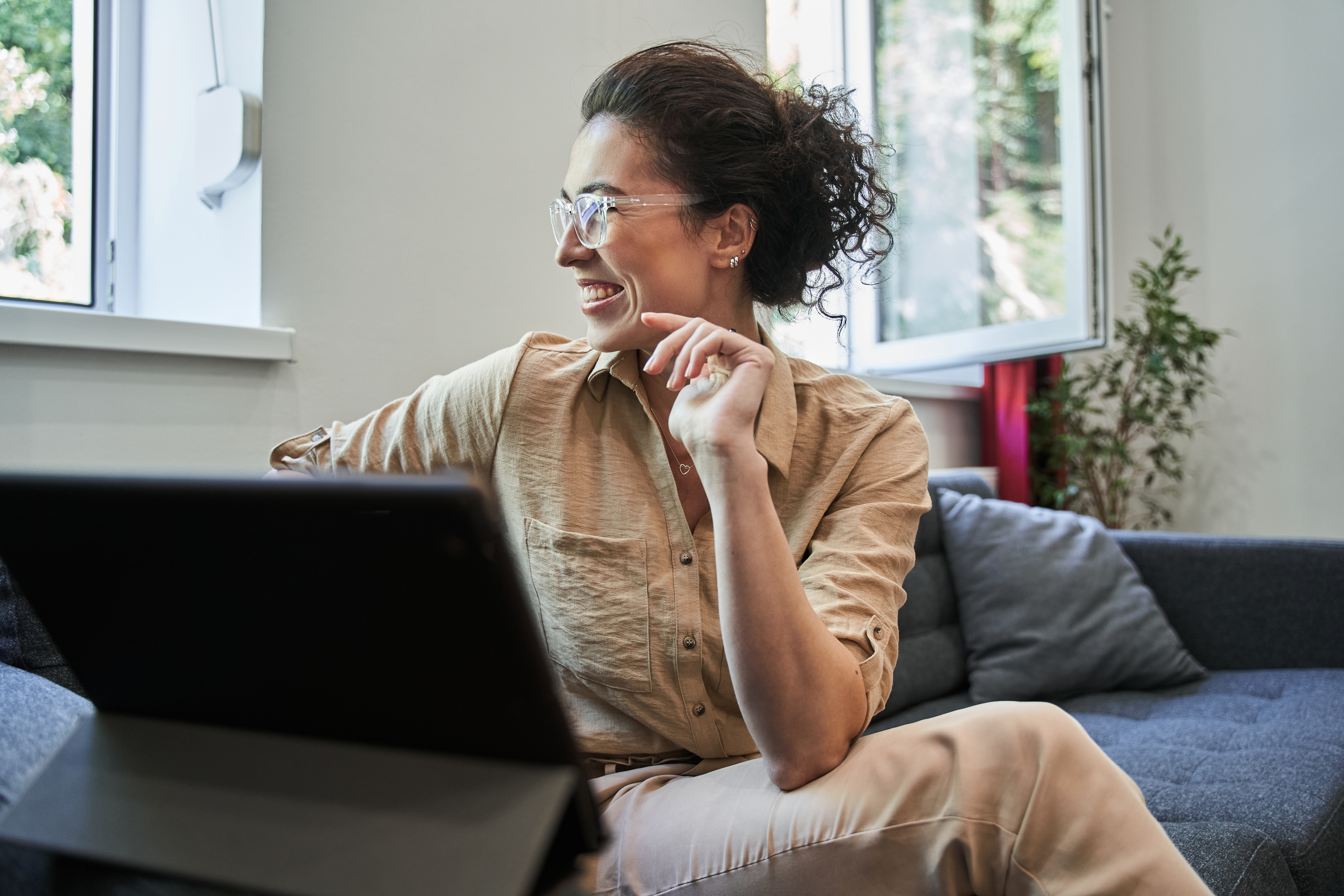 Happy female therapist looking at the window and smiling while chatting online